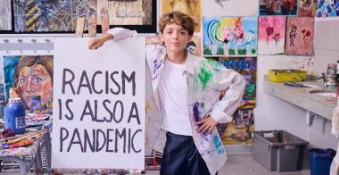 Art student painting a sign that reads Racism is also a pandemic.
